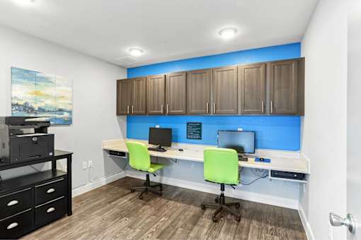 A room with a desk, chairs, and a computer setup.