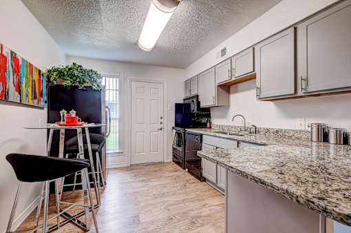 A kitchen with granite countertops and a black fridge.