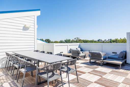 A white table with chairs and a couch on a patio.