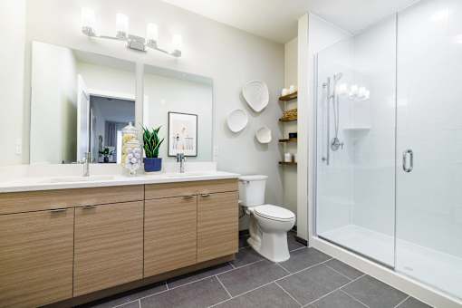 A bathroom with a white sink, toilet, and a glass shower stall.