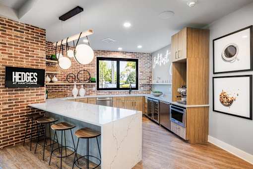 A kitchen with a white countertop and a brick wall.