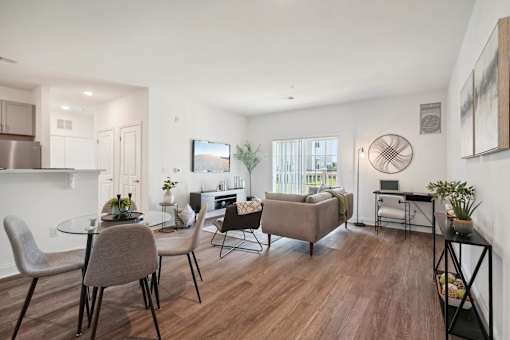 A modern living room with a glass table and grey chairs.