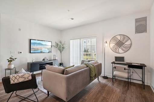 A living room with a couch, chair, and a television on the wall.