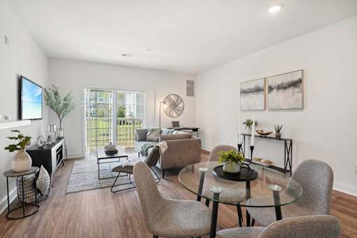 A modern living room with a glass table and grey chairs.