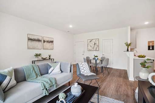 A living room with a grey couch, a coffee table, and a dining table with chairs.