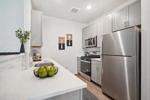 A kitchen with a stainless steel refrigerator and a bowl of bananas on the counter.