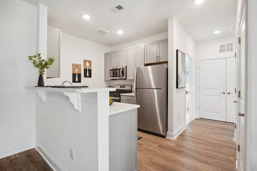 A modern kitchen with a refrigerator, sink, and cabinets.