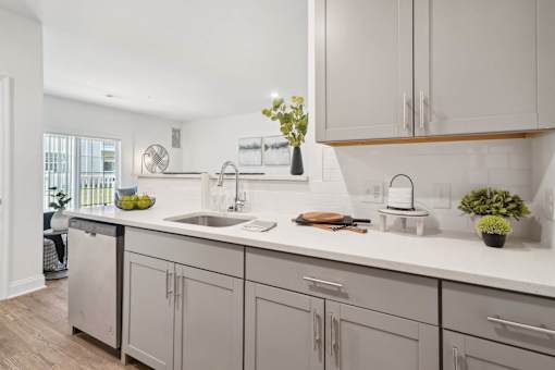 A kitchen with a white counter top and grey cabinets.