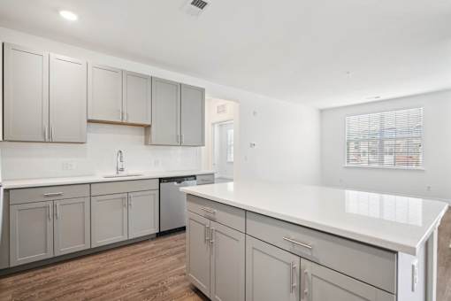 A kitchen with white countertops and grey cabinets.