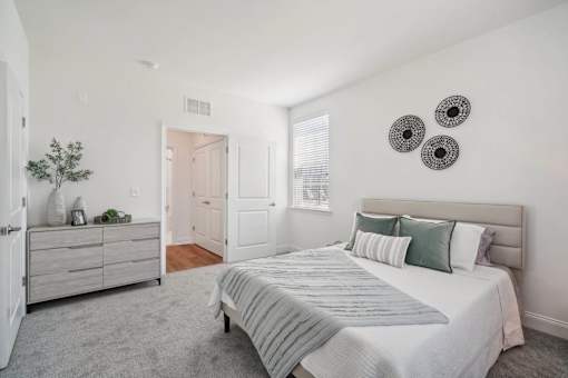 A bedroom with a bed, dresser, and two wall hangings.