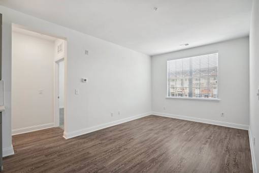 A room with wooden flooring and a window with blinds.