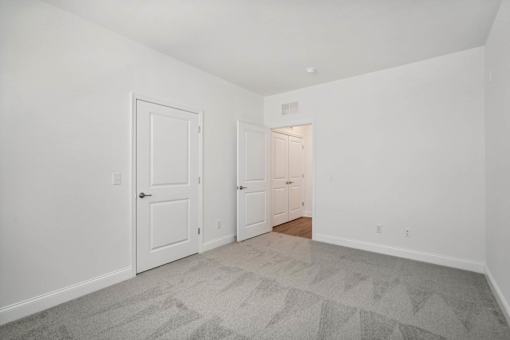 A room with two doors and a carpeted floor.