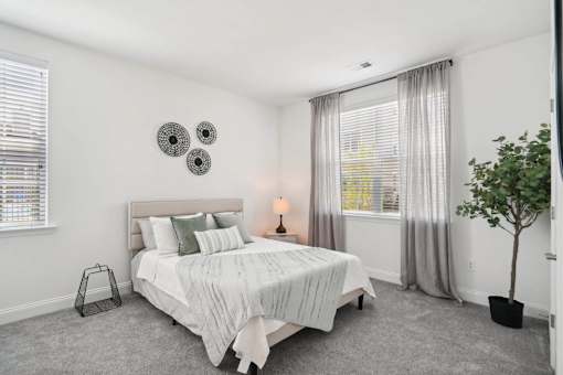 A bedroom with a bed, nightstand, and a plant.