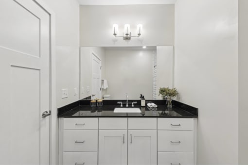 a white bathroom with a black counter top and a white sink