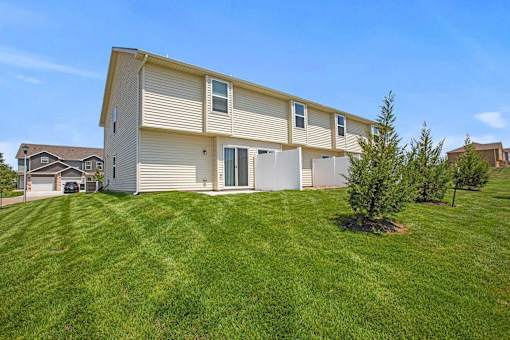 Dog-Friendly Apartments in Spring Hill, KS - Oak Woods - Backyard with Manicured Lawn, Trees, and Patio with Privacy Fence.