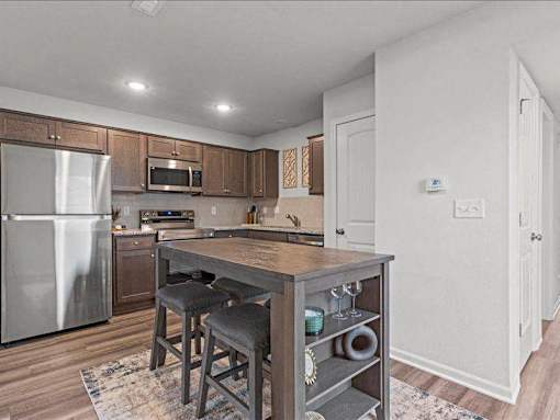 A kitchen with a wooden table and bar stools.