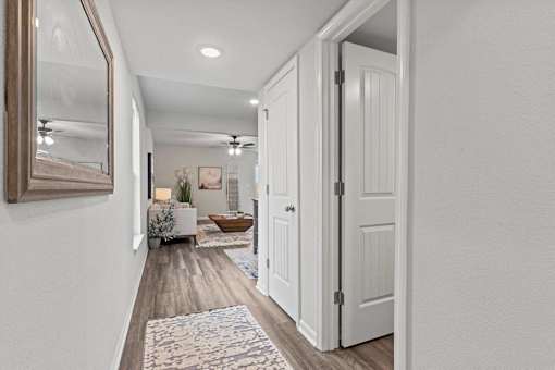 A hallway with a rug and a door on the right.