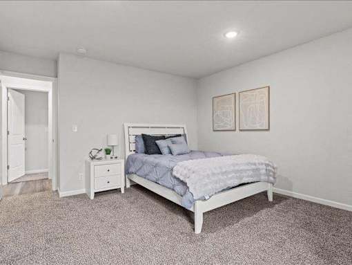 A bedroom with a bed, nightstand, and lamp.