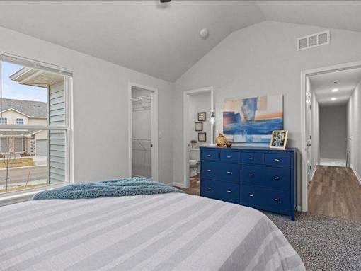 A bedroom with a blue bedspread and a blue dresser.