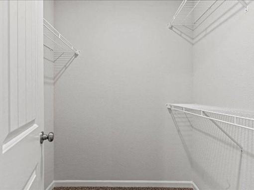 A white door is open to a white room with a white shelf.