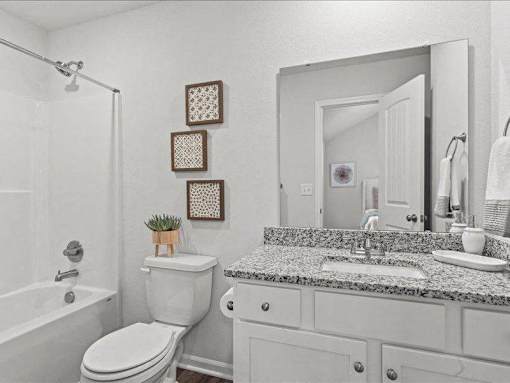 A white bathroom with a toilet, sink, and mirror.