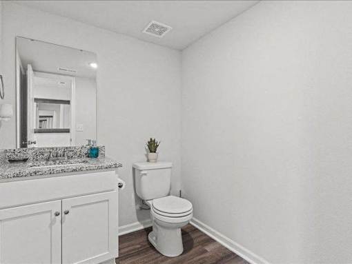 A white toilet sits in a bathroom next to a sink and mirror.