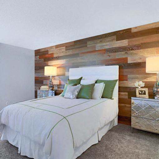A bedroom with a white bed and a wooden wall.