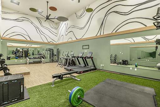 A gym with a green weight and a mirror on the wall.