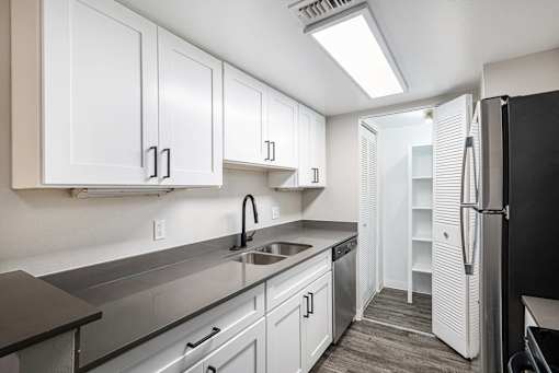 A kitchen with white cabinets and a black refrigerator.