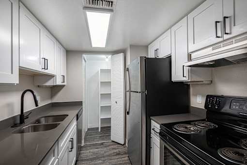 A kitchen with black appliances and white cabinets.