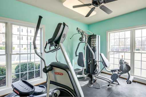 A home gym with a treadmill, elliptical trainer, and other exercise equipment.