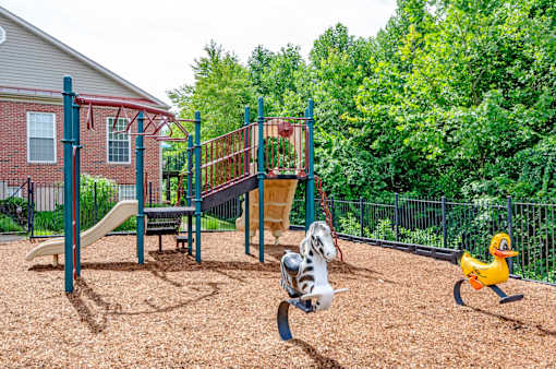 A playground with a slide, swings, and a seesaw.
