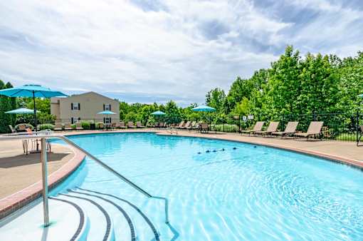 A large swimming pool with a metal railing and sun loungers.