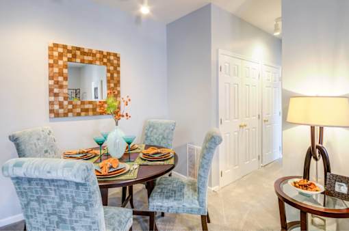 A dining room with a table set for two and a mirror above it.