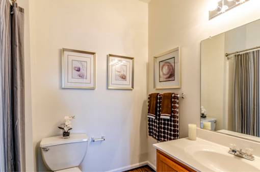 A bathroom with a toilet, sink, and three pictures on the wall.