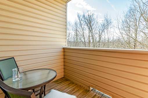 A table with a glass of water on it sits on a balcony.