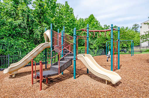 A playground with two slides and a climbing structure.