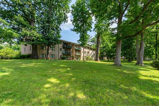 A grassy area in front of a building with trees on the sides.