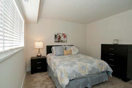 A bedroom with a bed, nightstand, and a lamp.