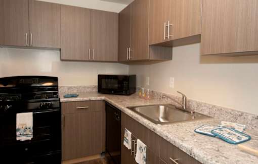 A kitchen with a black stove and brown cabinets.