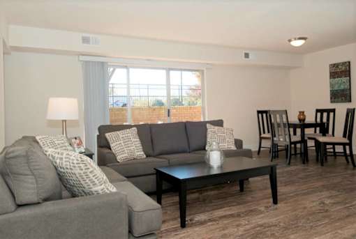 A living room with a grey couch, a black coffee table, and a lamp.