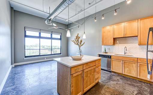 A kitchen with wooden cabinets and a countertop with a vase of flowers on it.