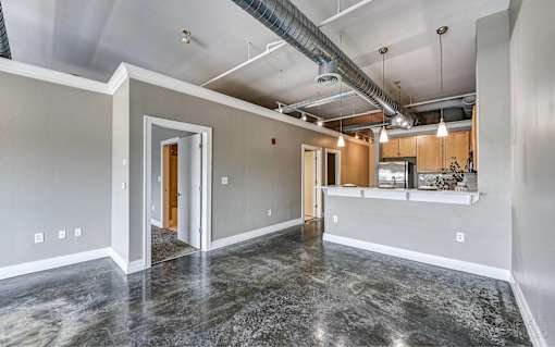 A spacious room with marble flooring and a kitchen area in the background.