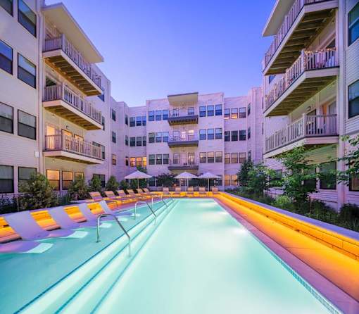 A long, narrow pool is the centerpiece of a courtyard surrounded by apartment buildings.