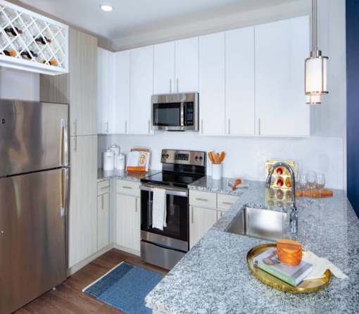 A modern kitchen with a granite countertop and stainless steel appliances.