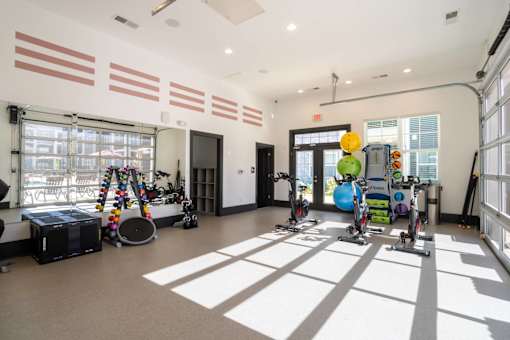 A room with exercise equipment and a large window letting in sunlight.