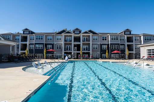 A large swimming pool in front of a multi-story apartment building.