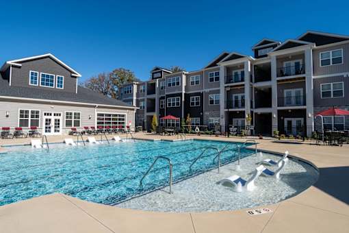 A swimming pool with a slide and a building in the background.