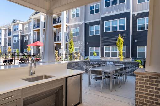 A modern outdoor kitchen area with a table and chairs.