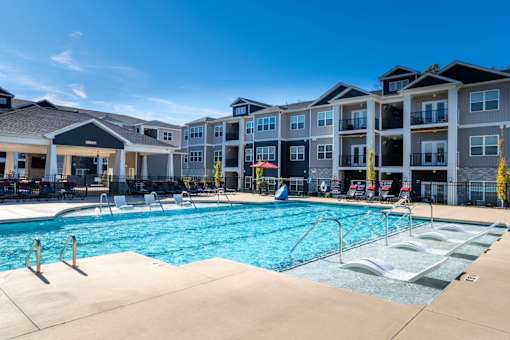 A large swimming pool in front of apartment buildings.